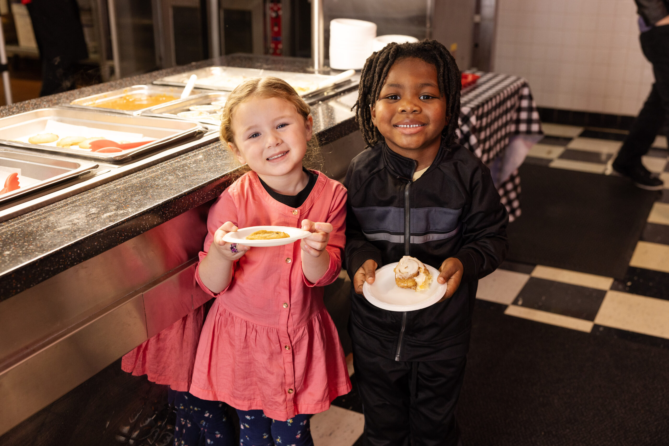Two kids smiling with dessert plates at the buffet at Incredible Food and Fun